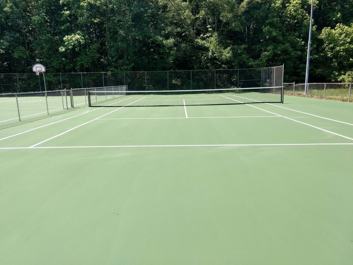 Same tennis court after resurfacing with fresh green surface and white lines
